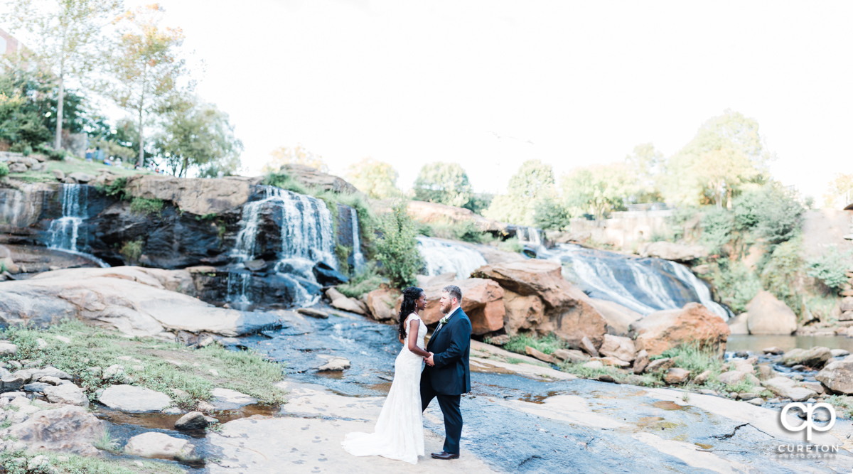 Bride and Groom standing in the waterfall at Falls Park on the Reedy after their wedding ceremony in downtown Greenville,SC.