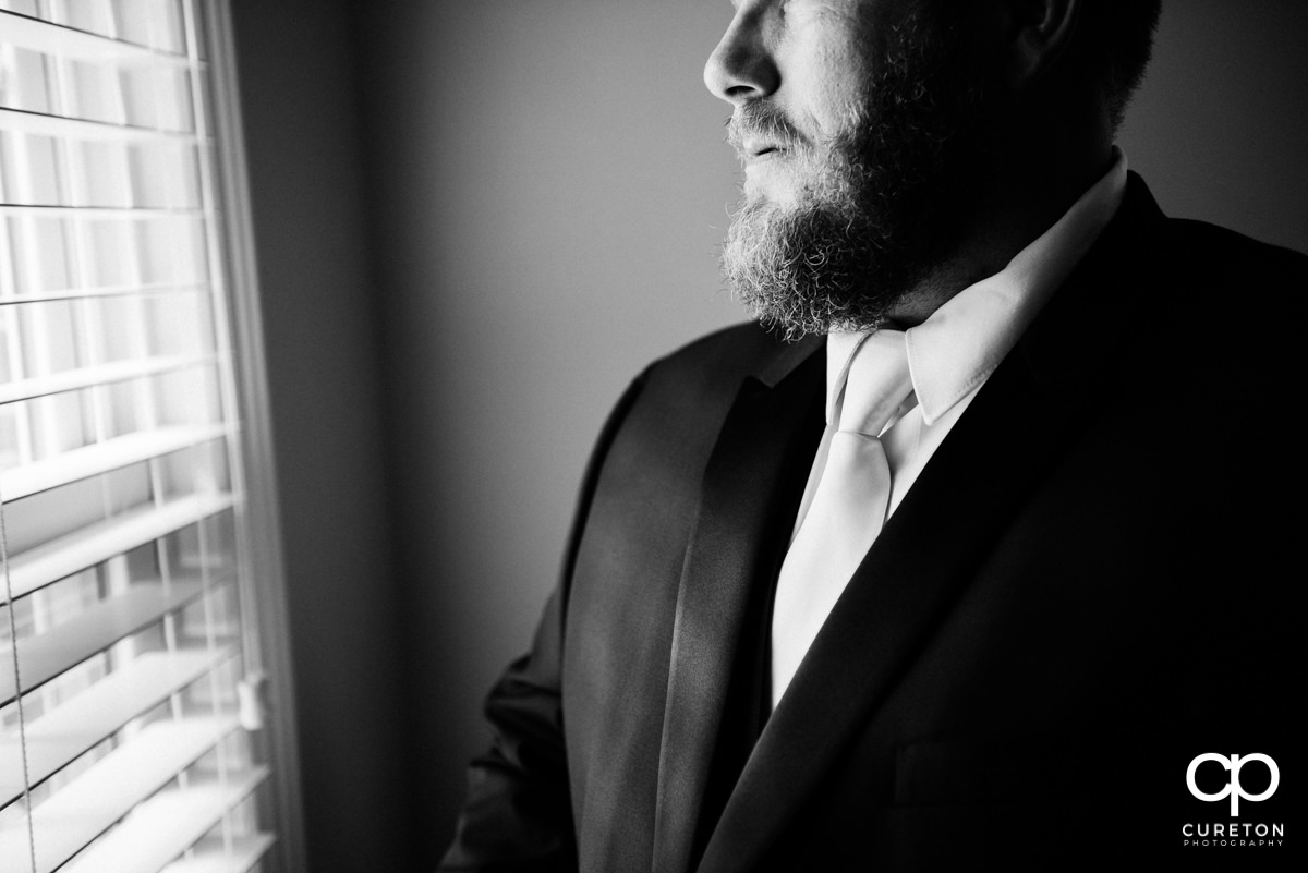 Groom looking out the window getting ready.