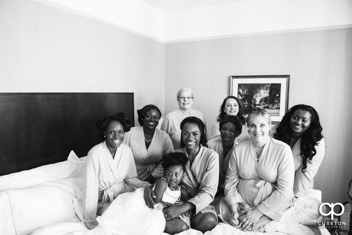 Bride and bridesmaids in their robes on the bed.