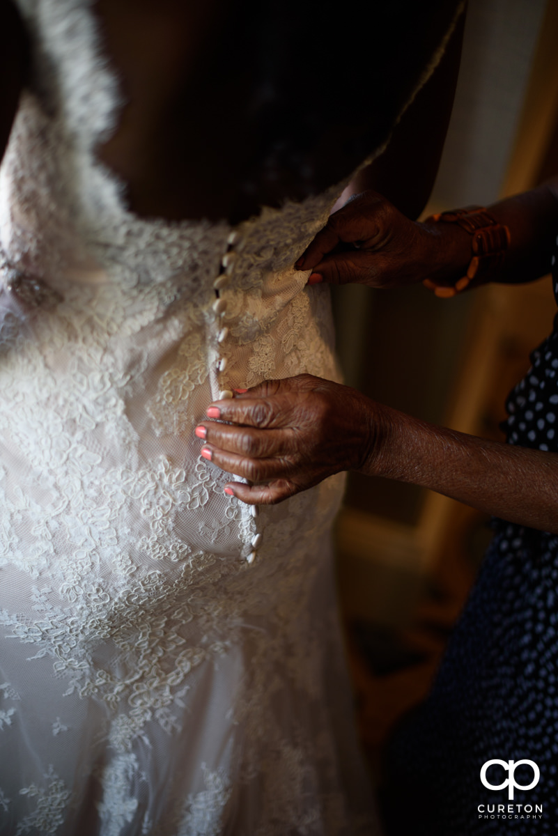 Bride's mother helping her with the dress.