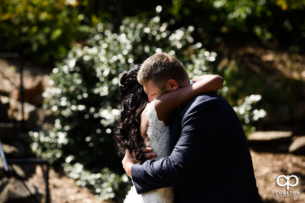 Groom hugging his bride in the park.