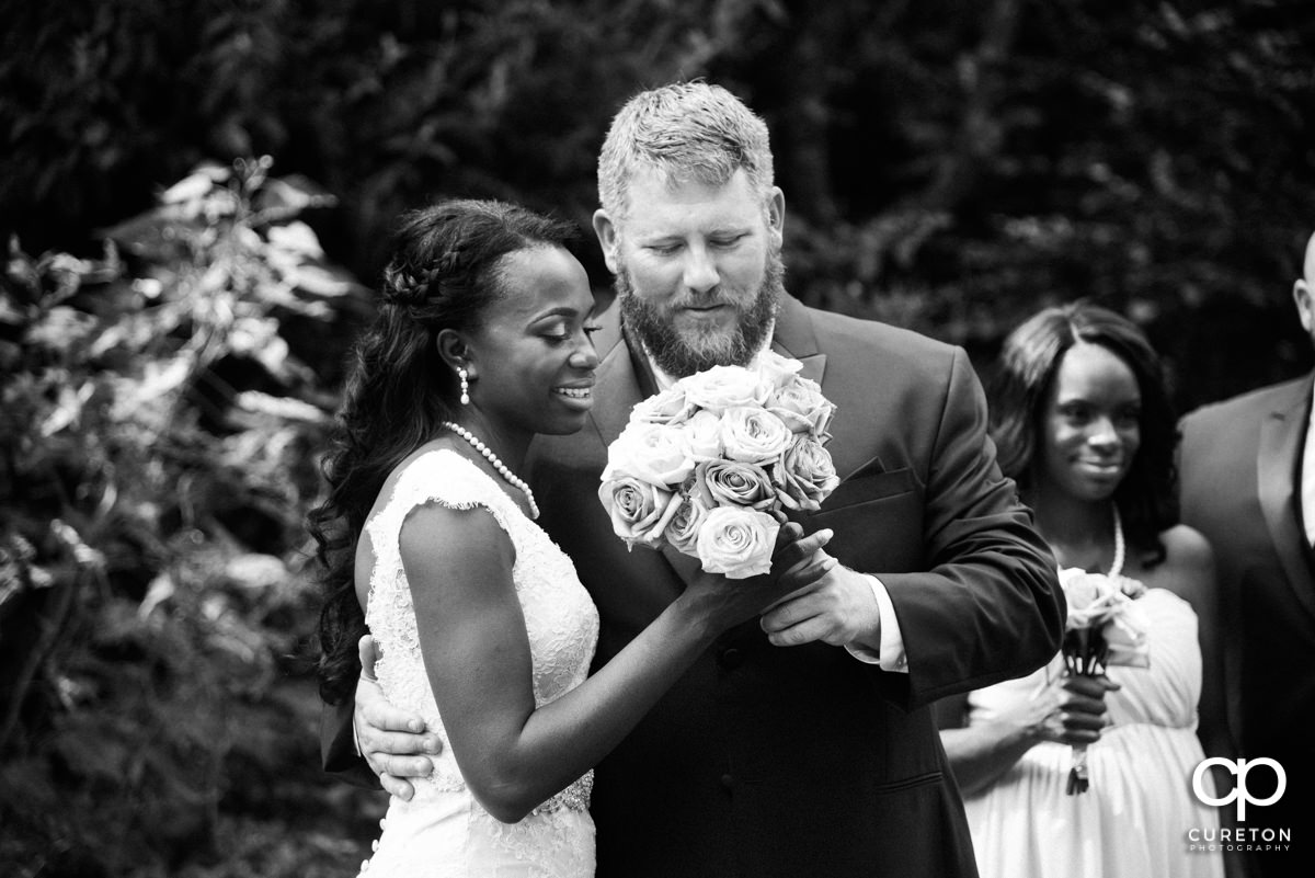 Bride and groom looking at her bouquet.