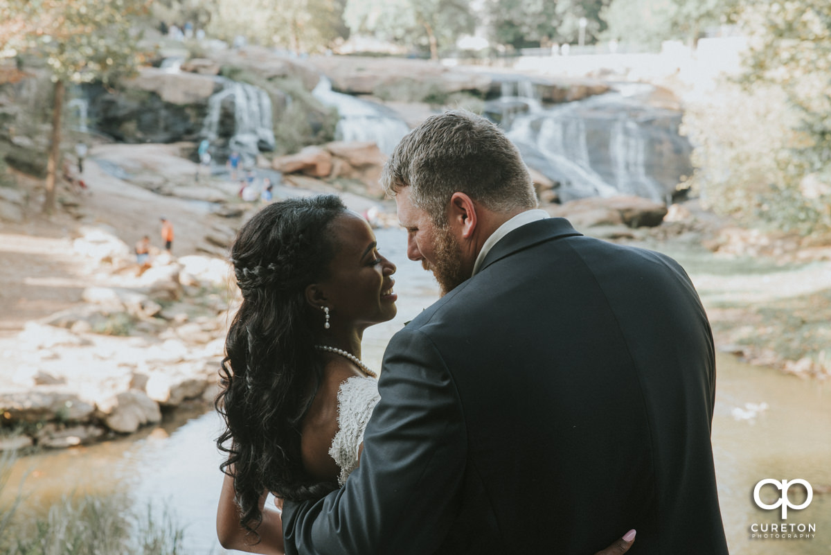 Bride and groom standing by the Reedy River.