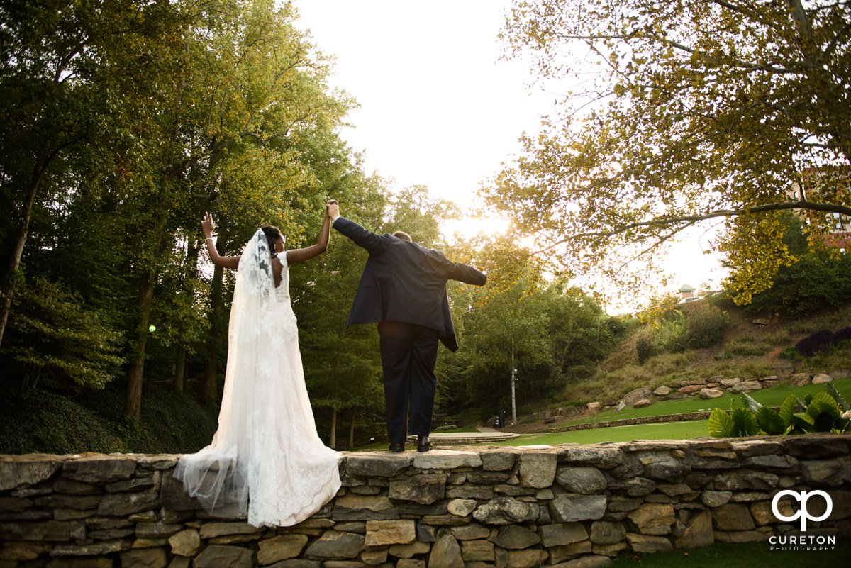 Bride and groom leaning over a bridge in Falls Park.