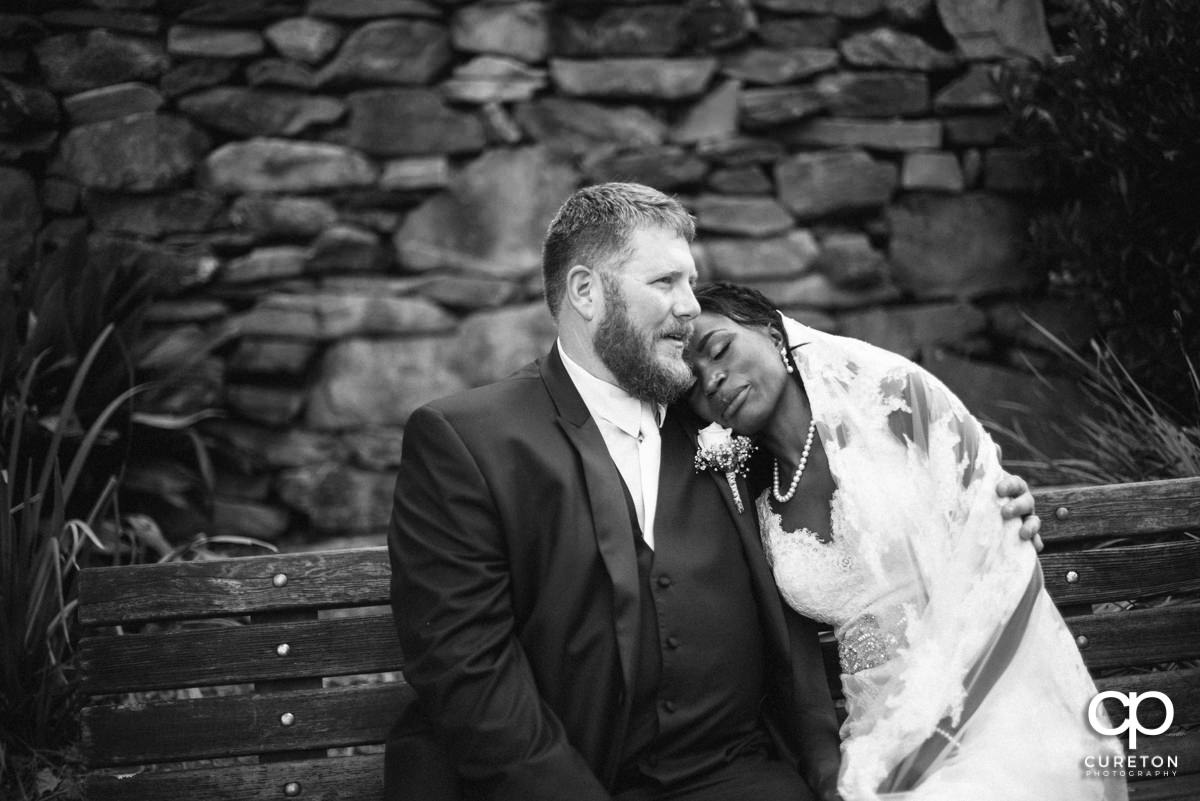 Couple sitting on a bench in the park after their wedding ceremony.