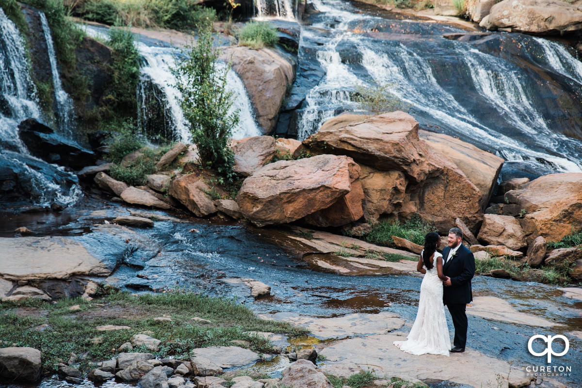 Bride and groom standing in the falls.