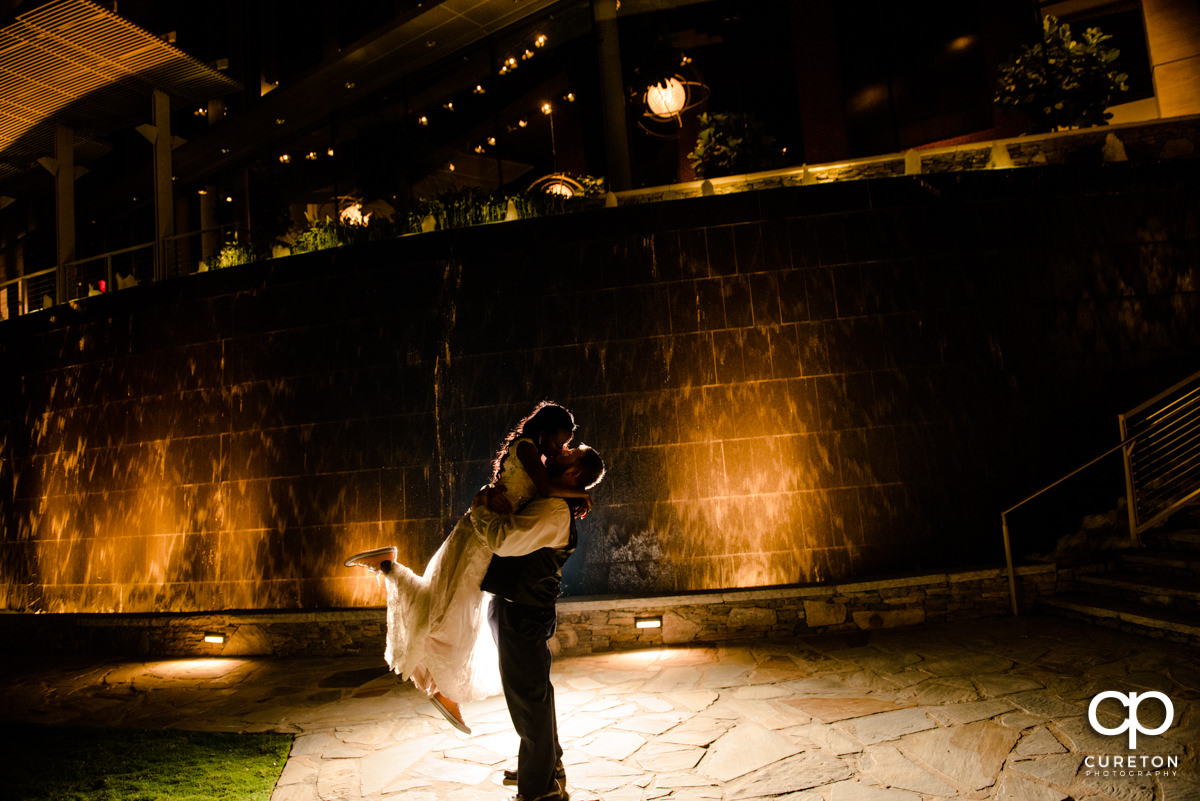 Groom lifting his bride in the park outside Larkin's on the river at the end of their reception.