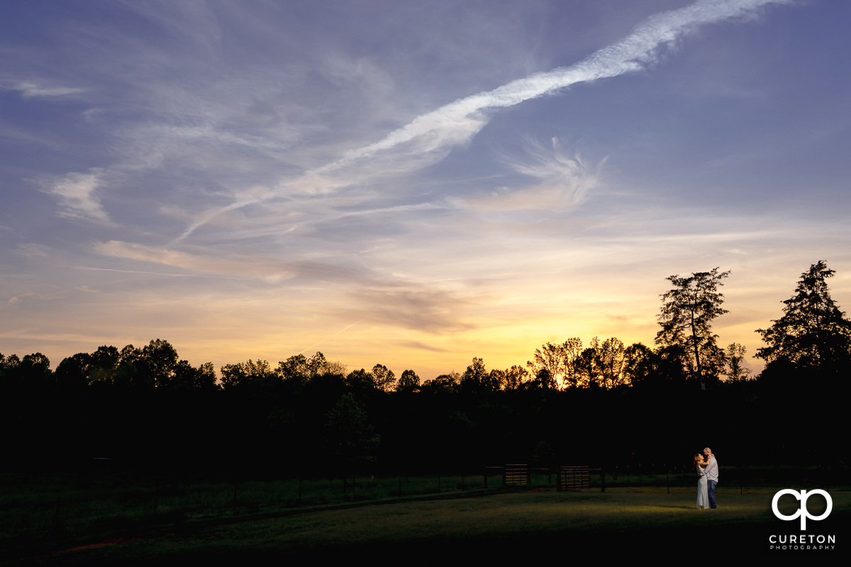 Future bride and groom dancing at sunset in a field during a family farm engagement session in Gray Court,SC.