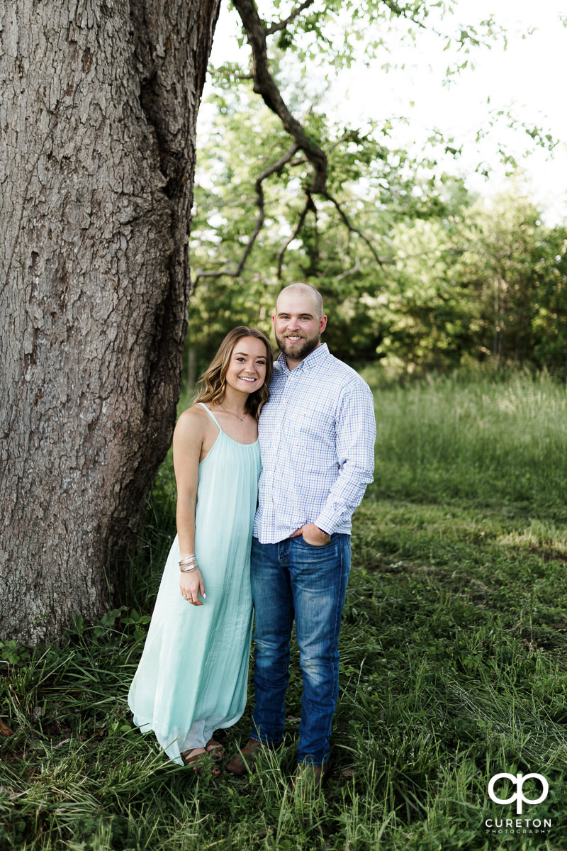 Man and his fiancee next to an oak tree.