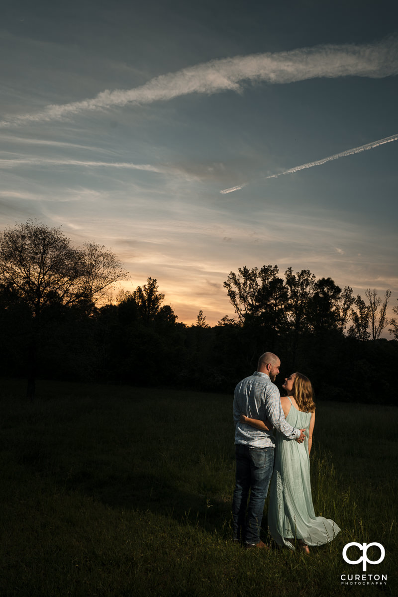 Engaged couple dancing underneath a sunset sky during a family farm engagement session in Gray Court,SC.