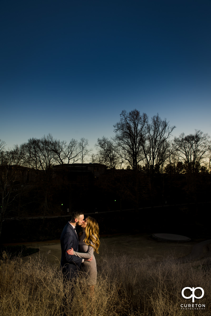 Future bride and groom standing in some tall grass during a Falls Park engagement session in downtown Greenville,SC.