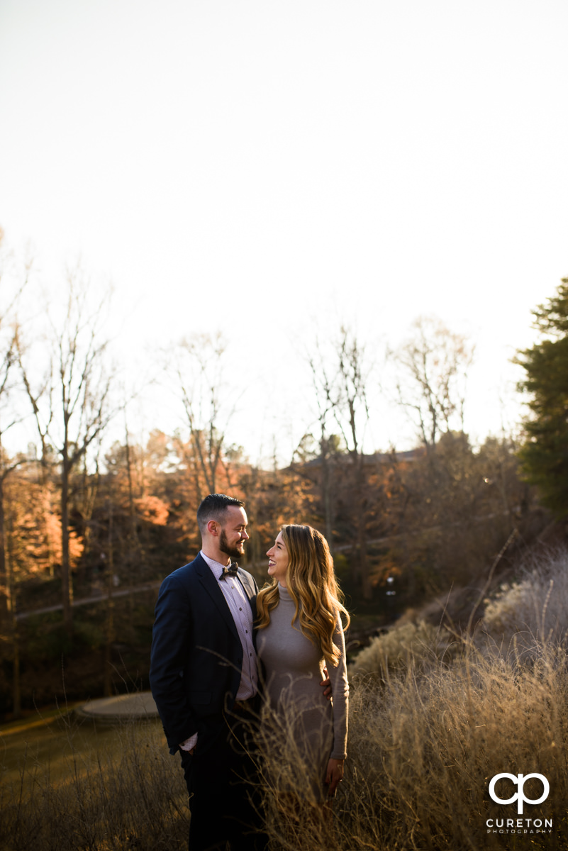 Future husband and wife standing in glowing sunlight during an engagement session in Falls Park in downtown Greenville,SC.
