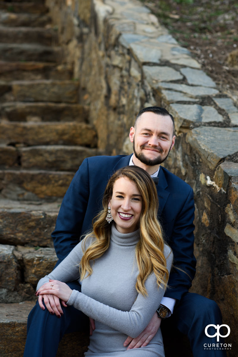 Engaged couple sitting on the steps in the park.