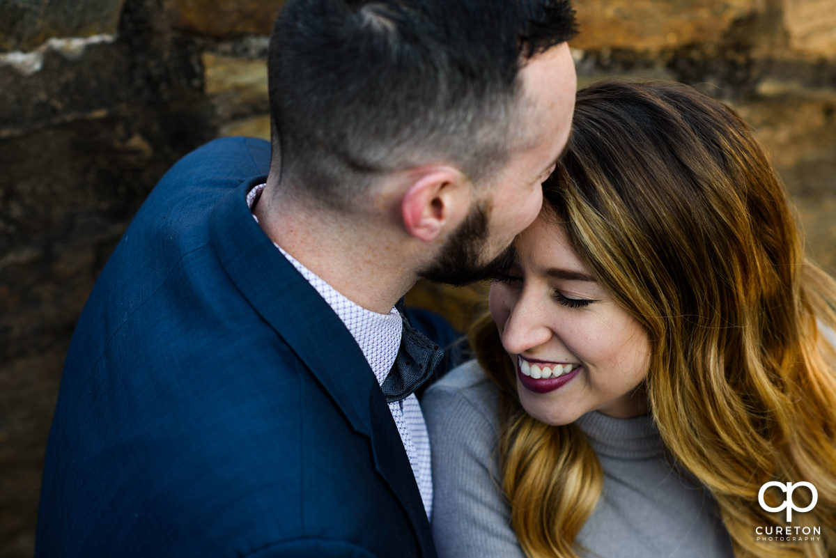 Groom kissing his bride on the forehead.