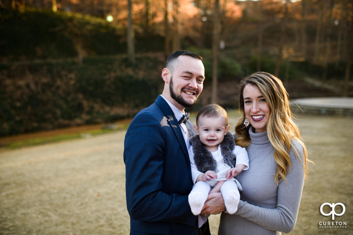 Engaged couple holding their daughter.