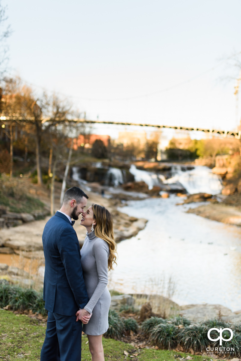 Engaged couple snuggling in front of the bride in Falls Park.