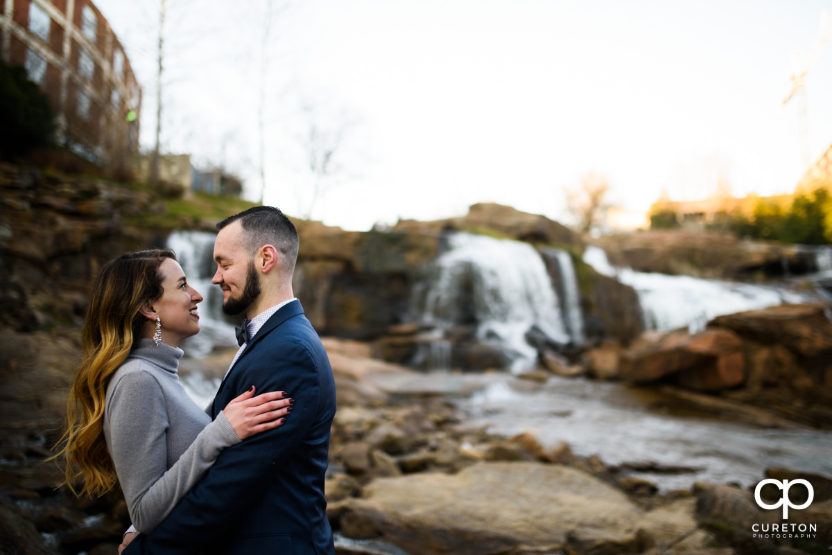 Engaged couple standing in front of the falls in Falls Park in downtown Greenville,SC.