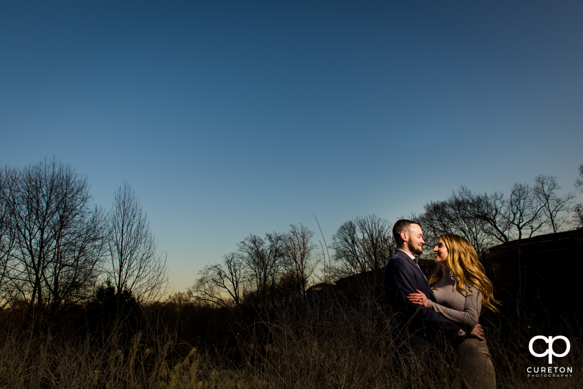 Man holding his fiancee at sunset during an engagement session.