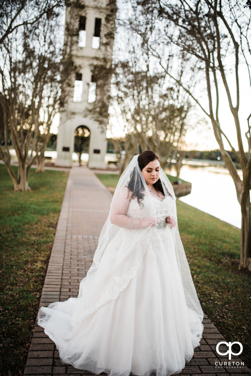 Bride holding onto her long veil in front of the bell tower at Furman during her bridal session.