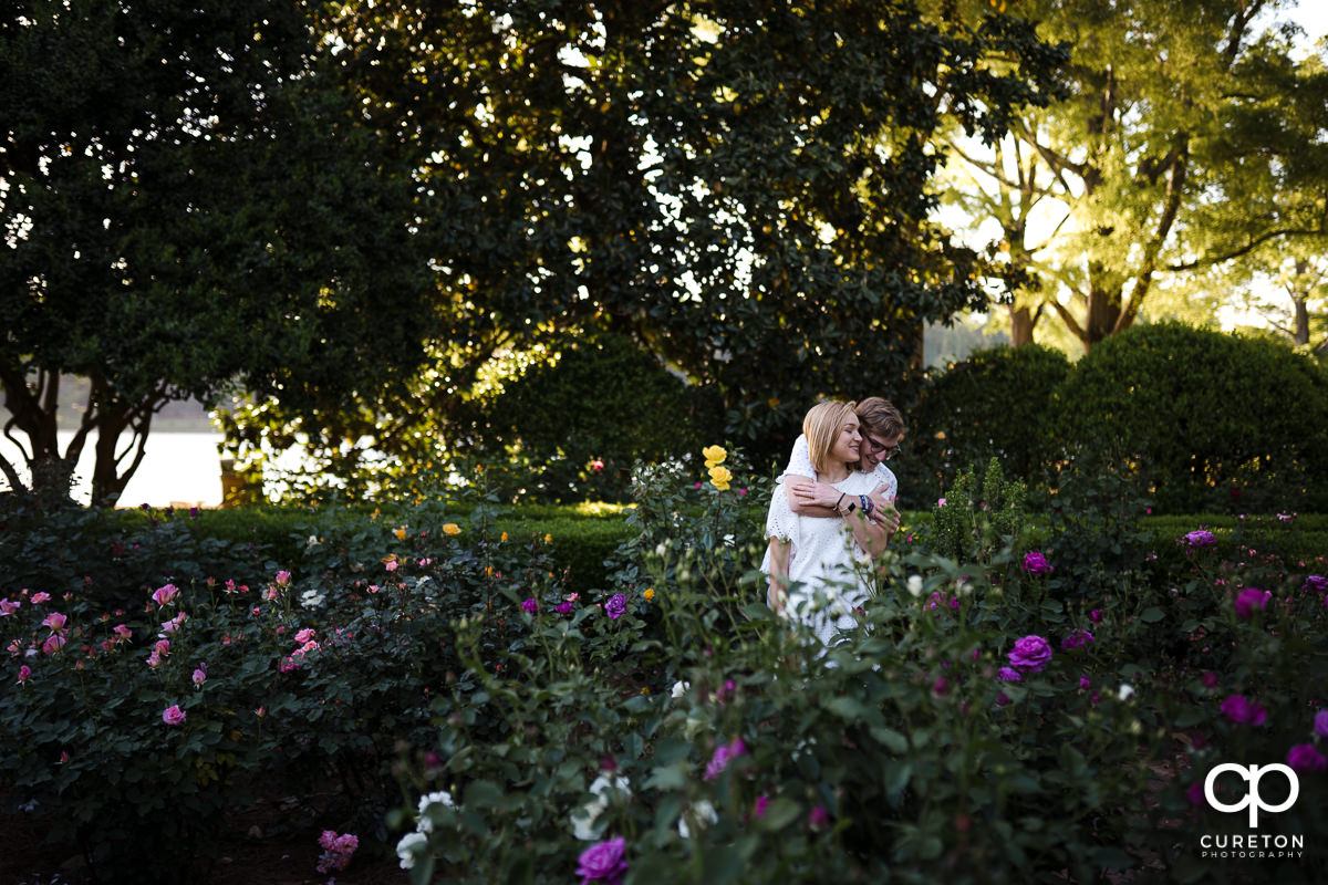 Engaged couple hugging in the rose garden during their college graduation and engagement session at Furman University.