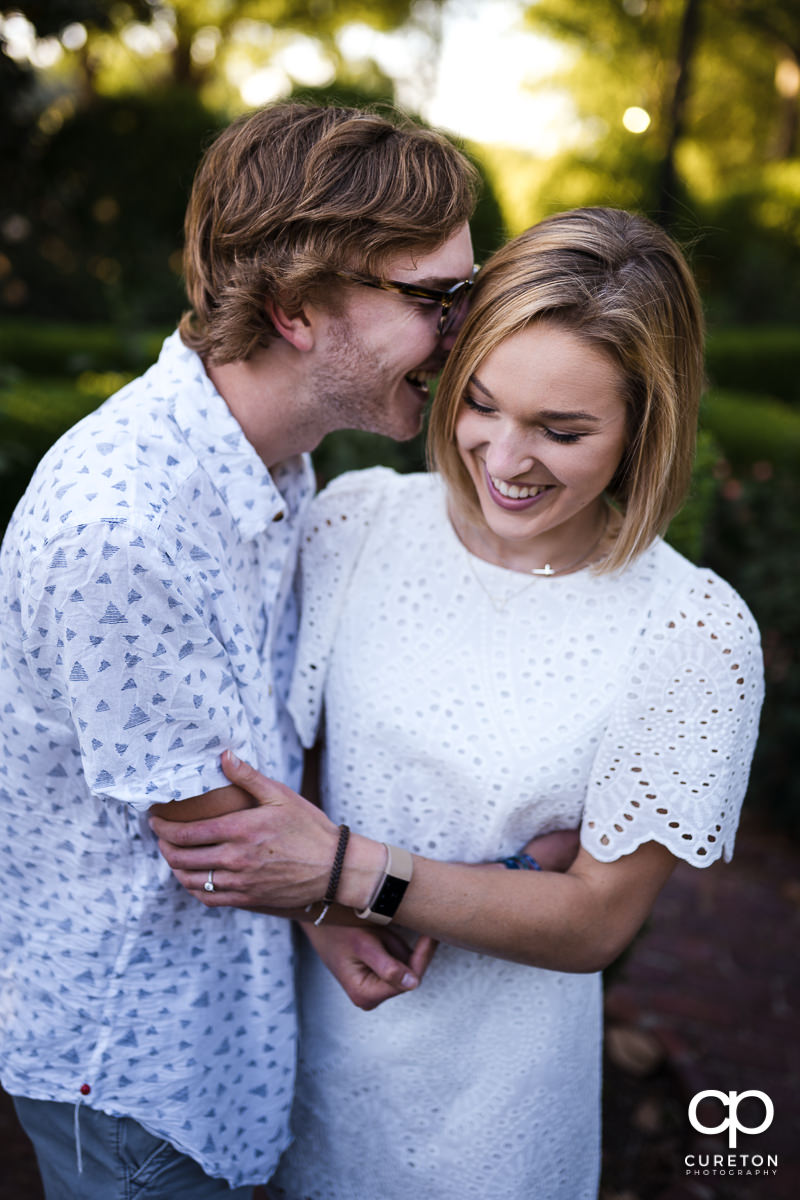 Two engaged students laughing during their college graduation and engagement session at Furman University.