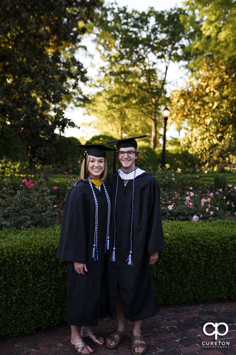 Two students in their cap and gown during their college graduation and engagement session at Furman University.