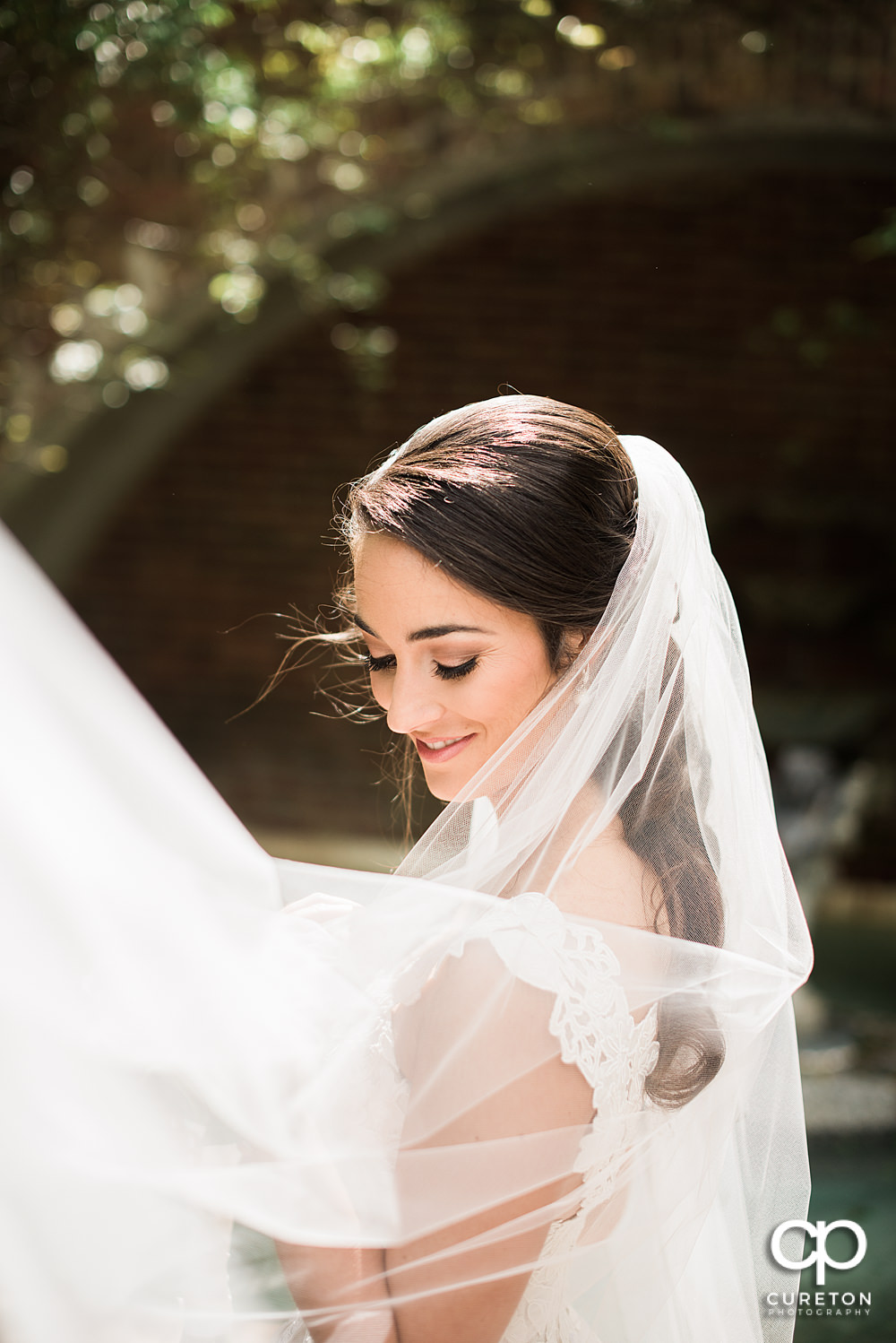 Bride smiling with her veil blowing in the rose garden at Furman.