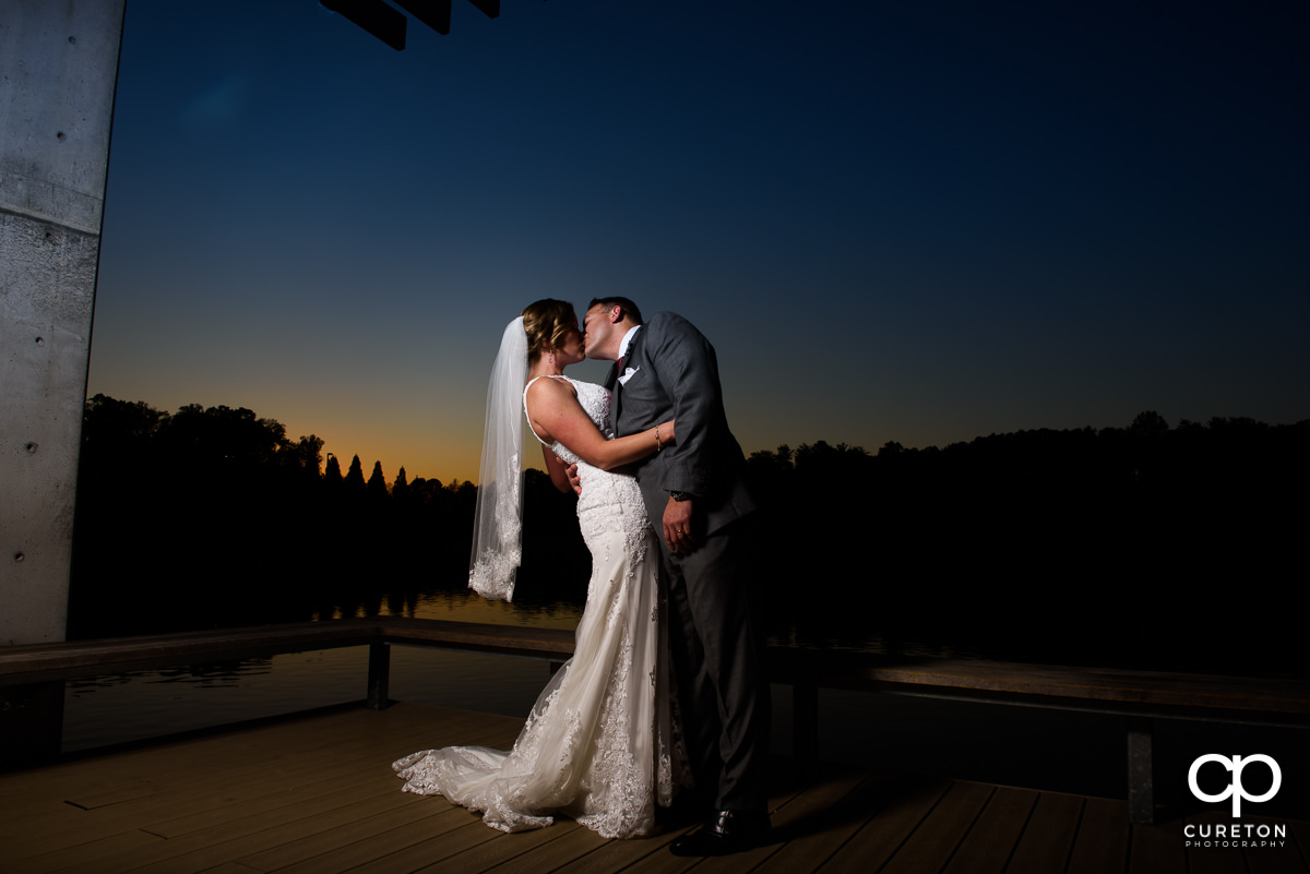 Bride and groom at sunset on a dock at the lake at the Furman campus.