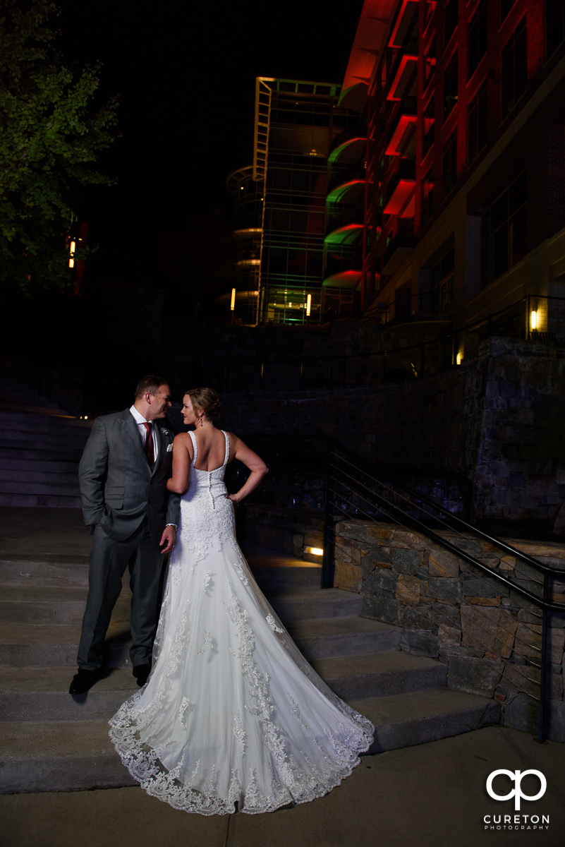 Bride showing the back of her dress with her groom in downtown Greenville.