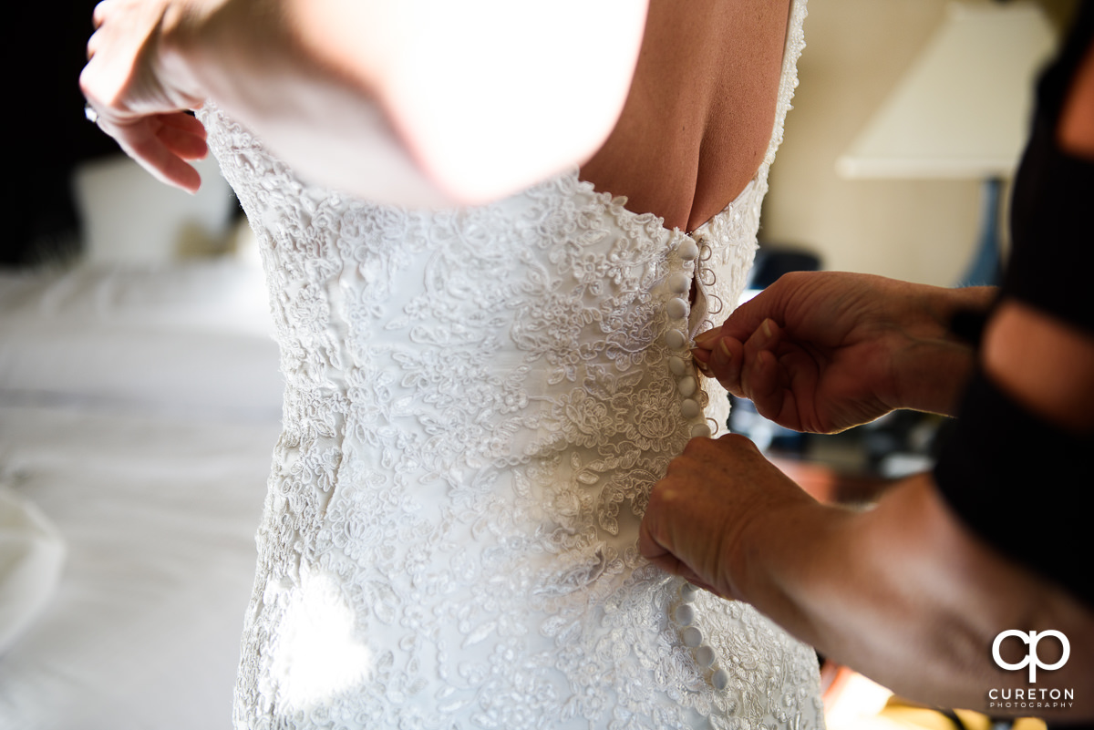Bride getting the back of her dress zipped up.