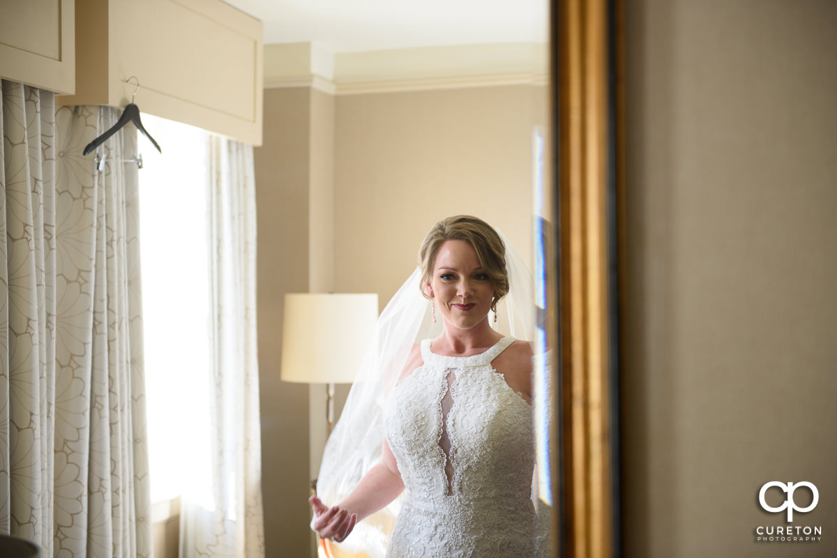 Bride looking at herself in the mirror at the Westin Poinsett Hotel.