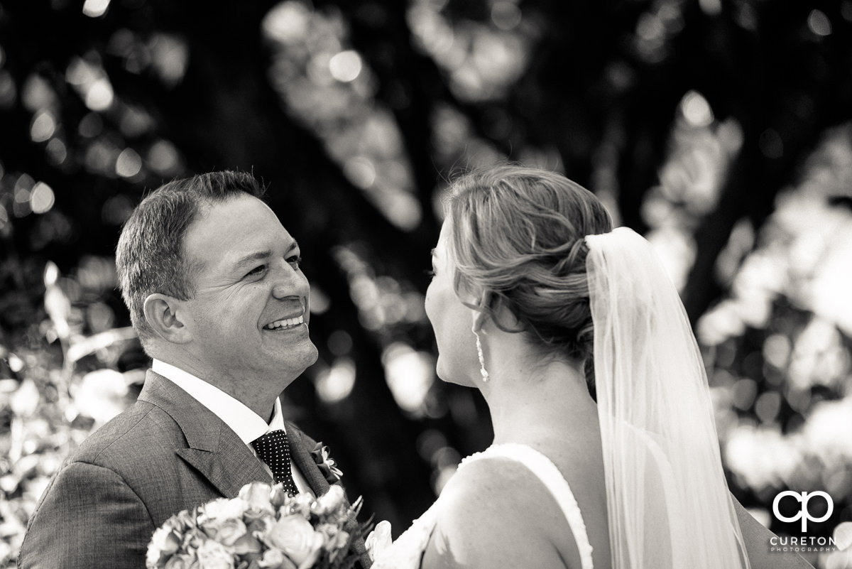 Groom smiling when he sees his bride for the first time in her dress.
