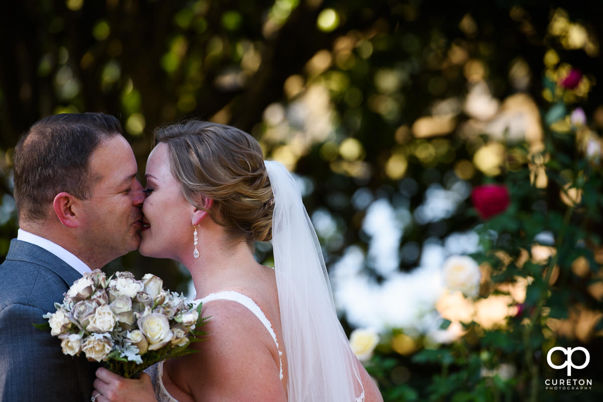 Bride and groom kissing in the rose garden.