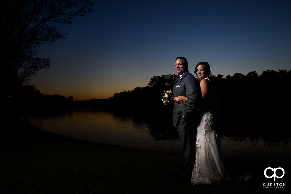 Bride and groom standing by the lake at Furman after their wedding.
