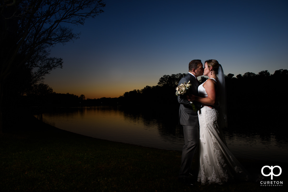 Bride and groom kissing at sunset.