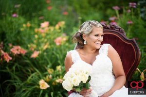 A bride in a victorian chair in flowers.