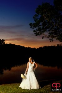 A bride posing by the lake at sunset during her Furman University bridal session..