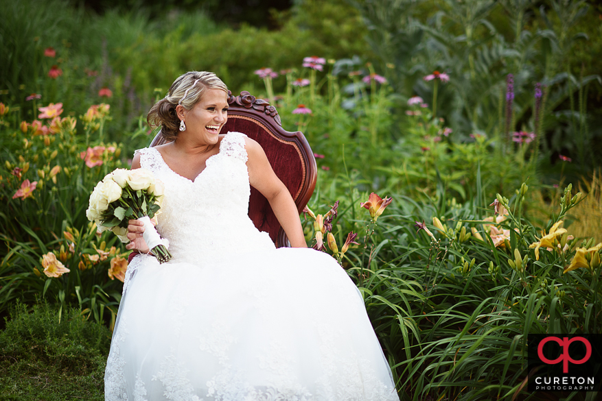 Bride posing in a red vintage chair in some flowers during her Furman University bridal session.