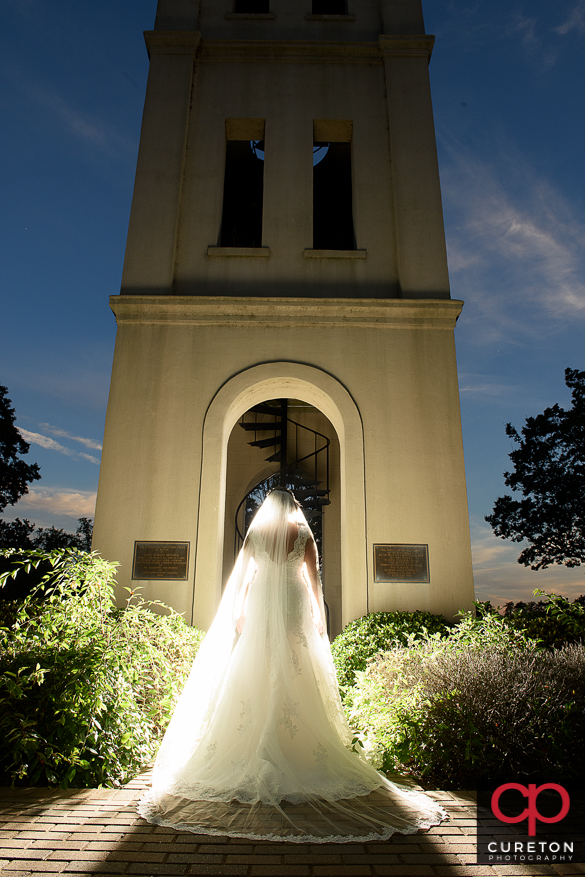 Backlit shot of a bride at the Bell Tower at Furman University by the lake.