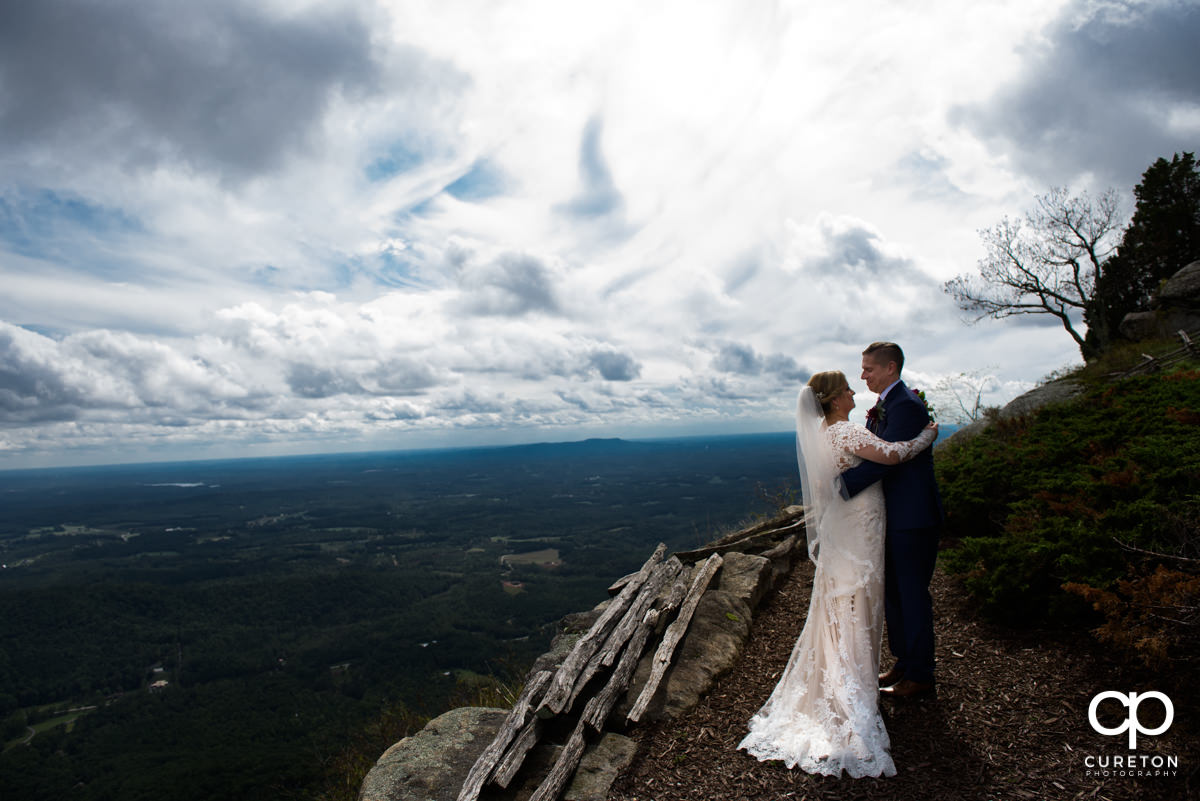 Bride and groom hugging on a mountaintop after their Glassy Chapel wedding.