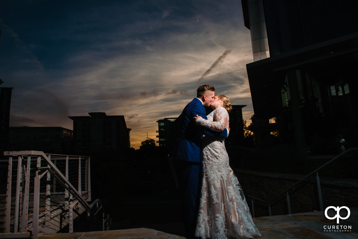 Groom kissing his bride in downtown Greenville at sunset at their wedding reception at Larkin's Cabaret Room in Greenville,SC.