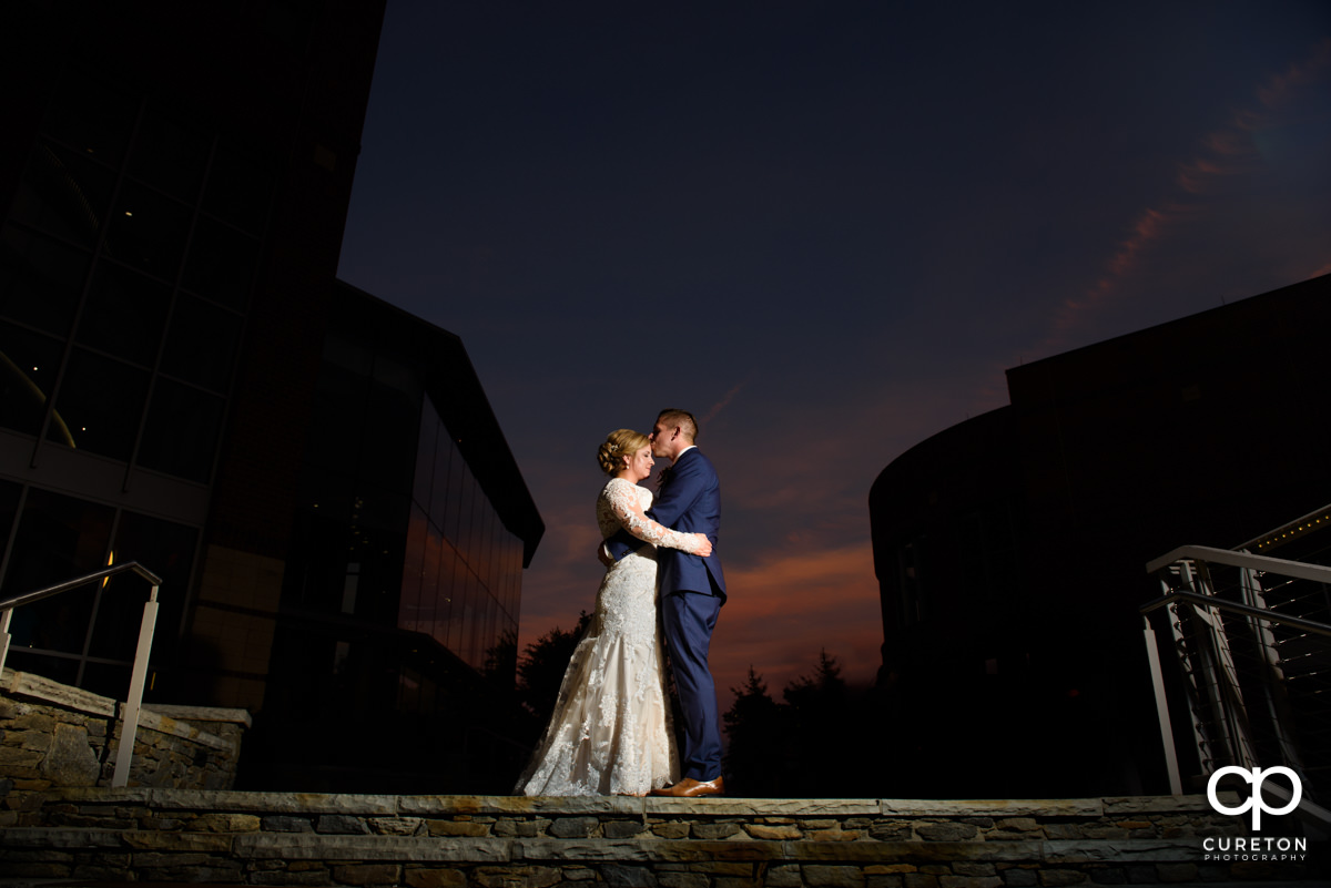 Groom kissing his bride on the forehead at sunset during their Larkin's Cabaret Room wedding reception in downtown Greenville,SC.
