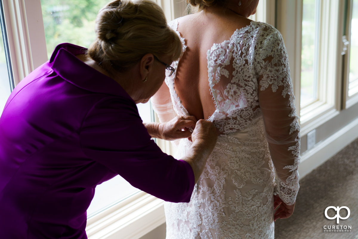 Bride's mom helping her zip her dress.