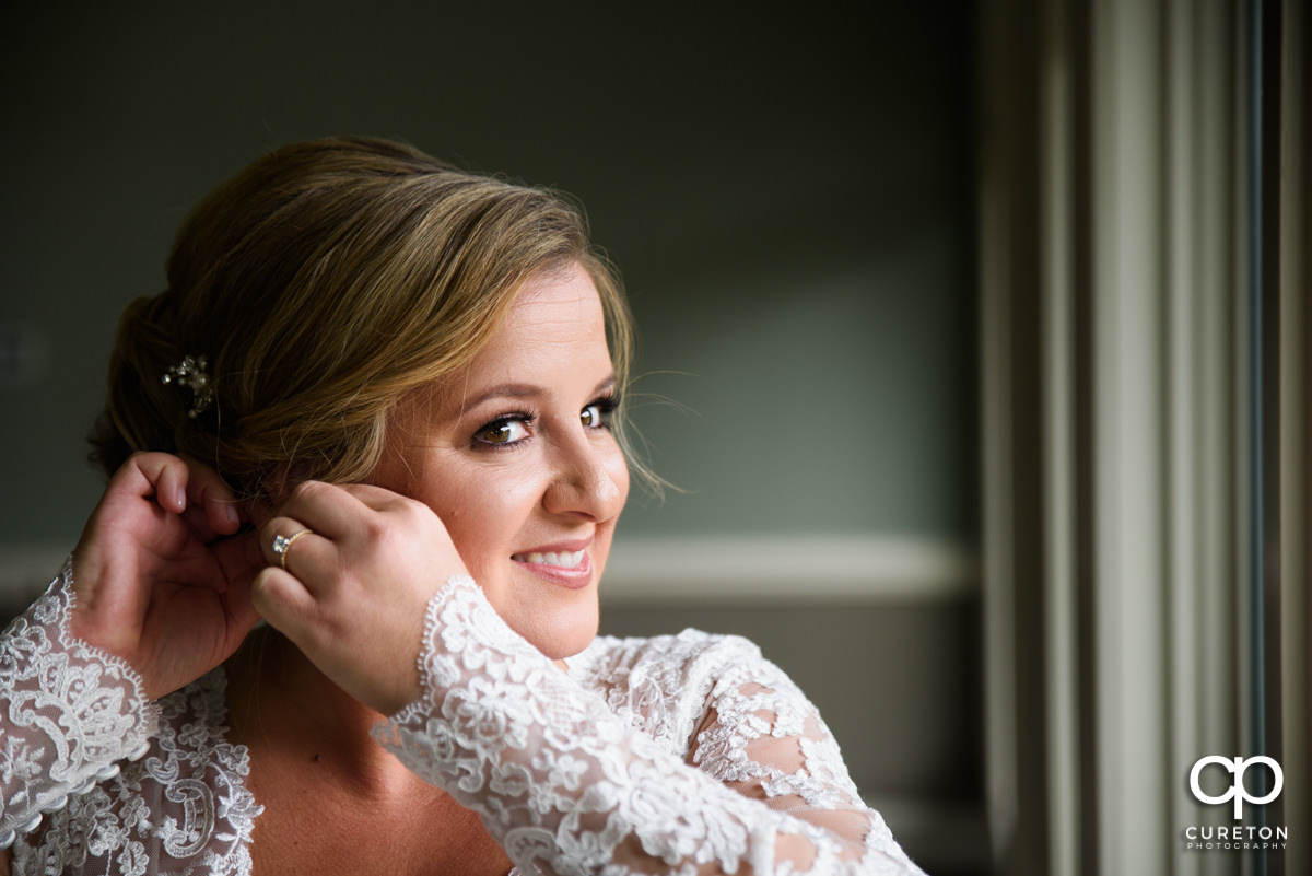 Bride putting her earrings in.