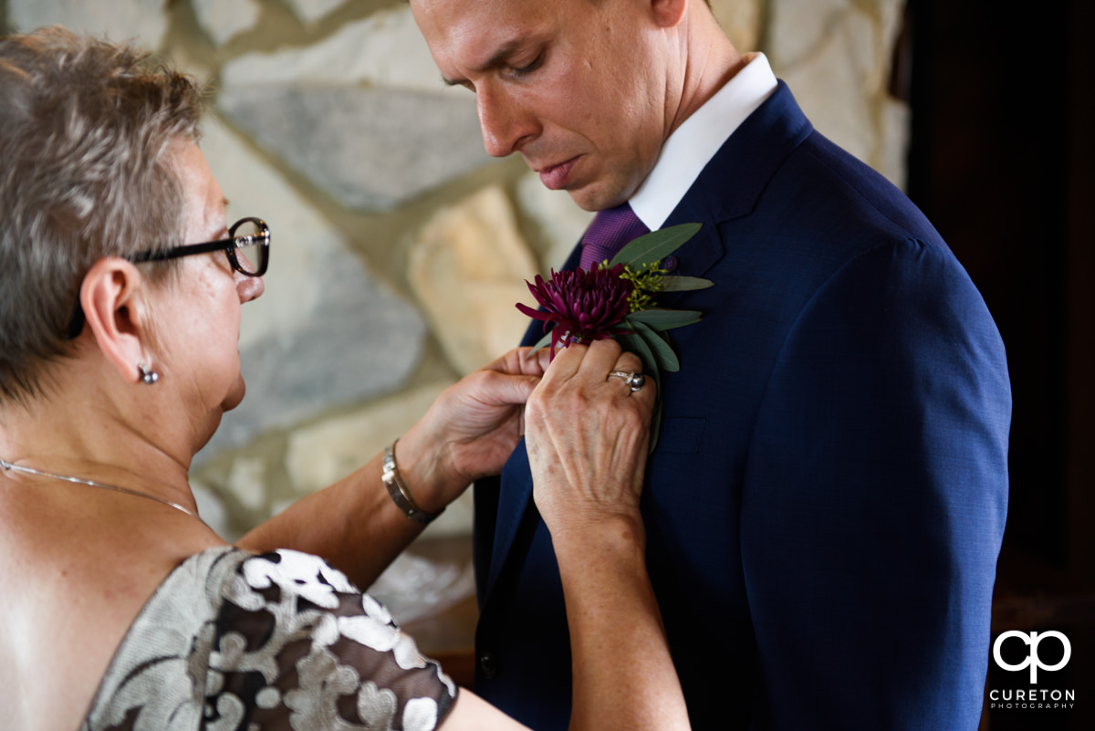 Groom's mom pinning his boutonniere on him.