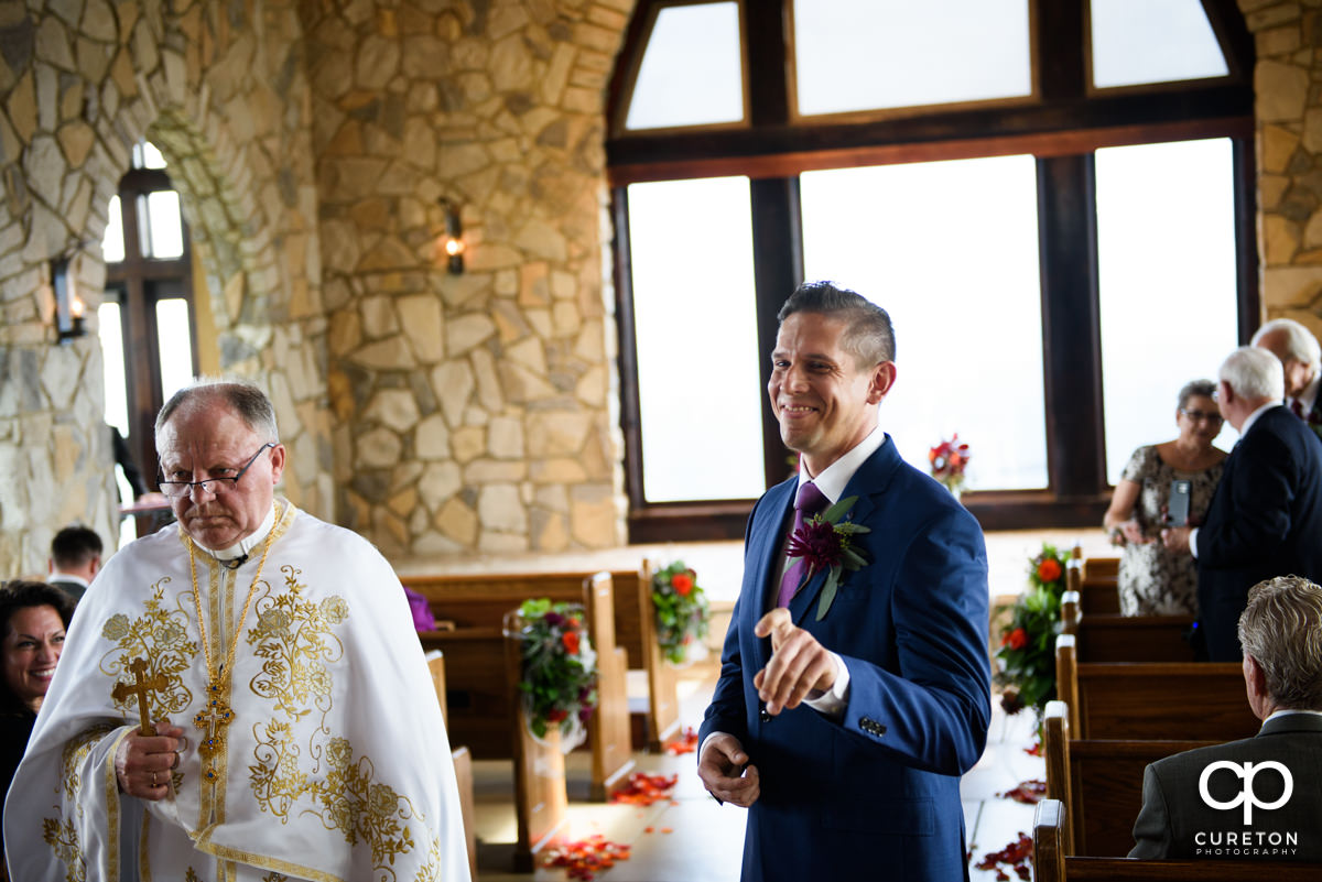 Groom smiling while standing in the aisle at Glassy Chapel.