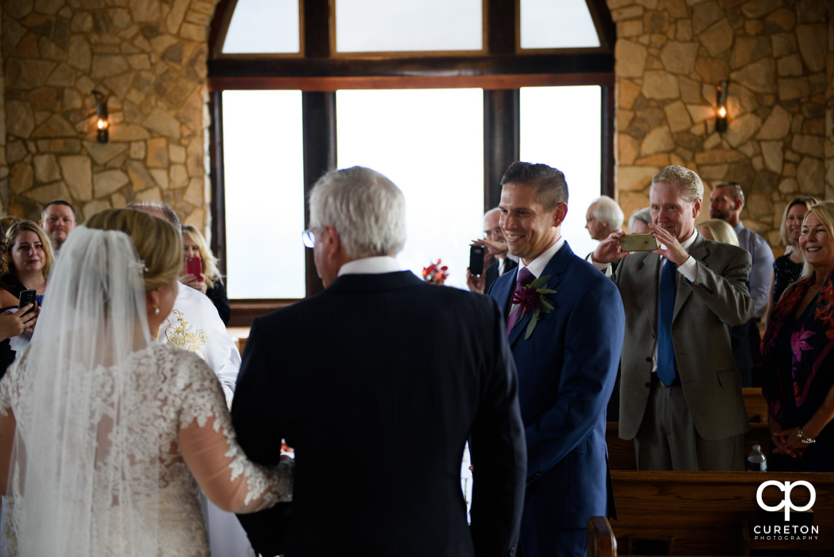 Groom smiling as he sees his bride in her dress for the first time at the ceremony.