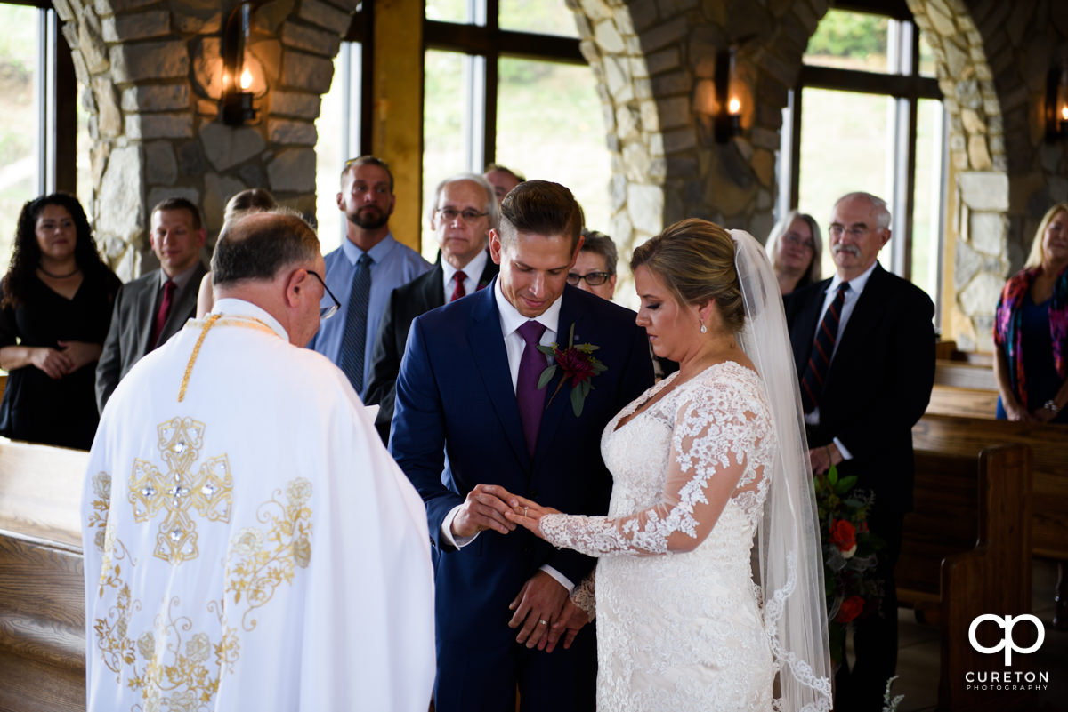 Groom putting a ring on the bride's finger.