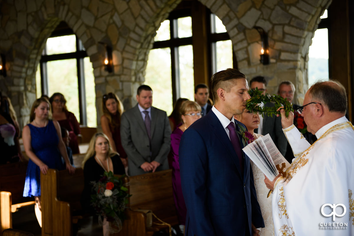 Groom kissing the crown at the wedding ceremony.