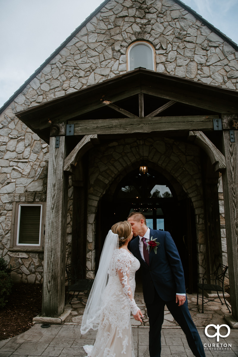 Bride and groom kissing outside of the chapel.